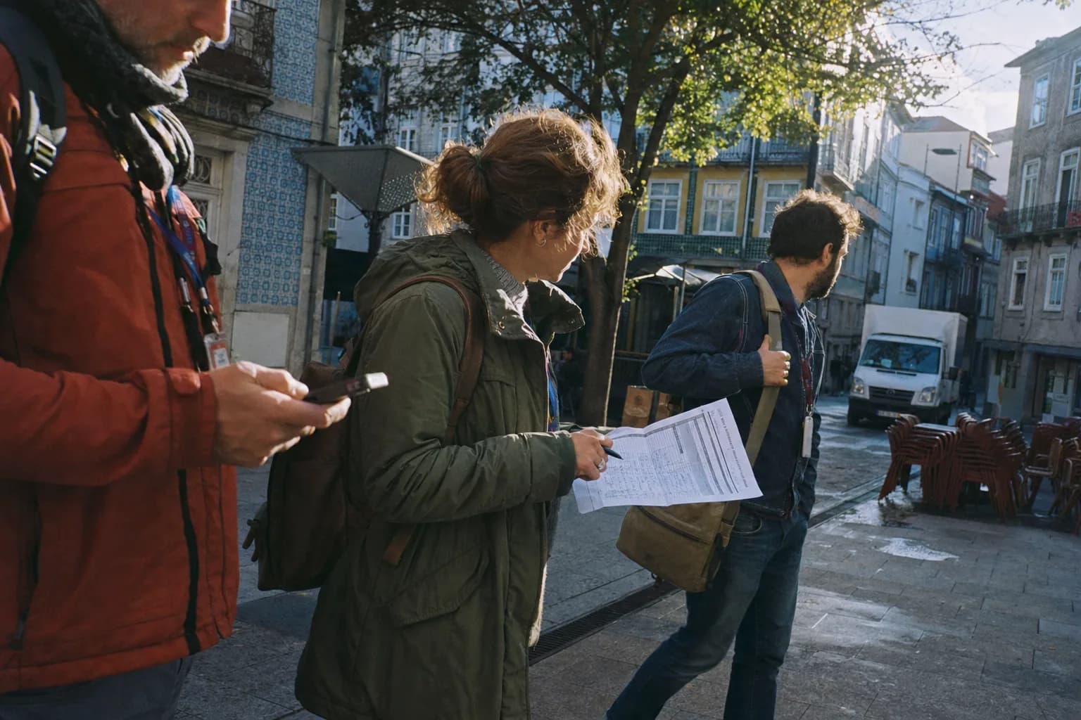 Freelance tour guides checking a phone and printed schedule on a Porto street